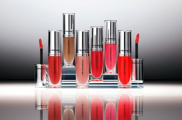 Set of lip glosses with applicators on a reflective surface
